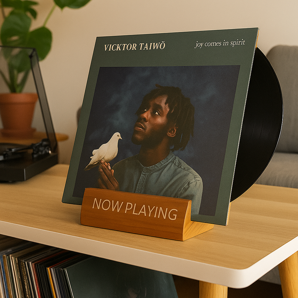 en houten 'Now Playing' display standaard op een licht houten meubel, die zowel de albumhoes als de vinylplaat zelf rechtop houdt.